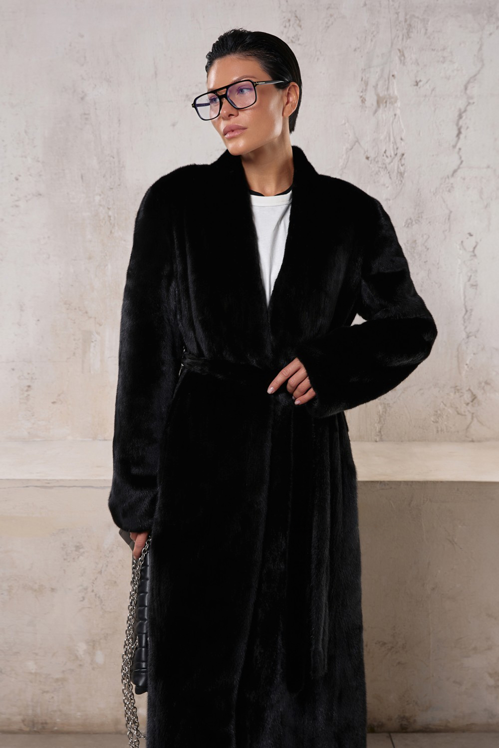 Elegant model wearing a long black mink coat, perfect for formal or sporty looks, showcasing luxury and sophistication.