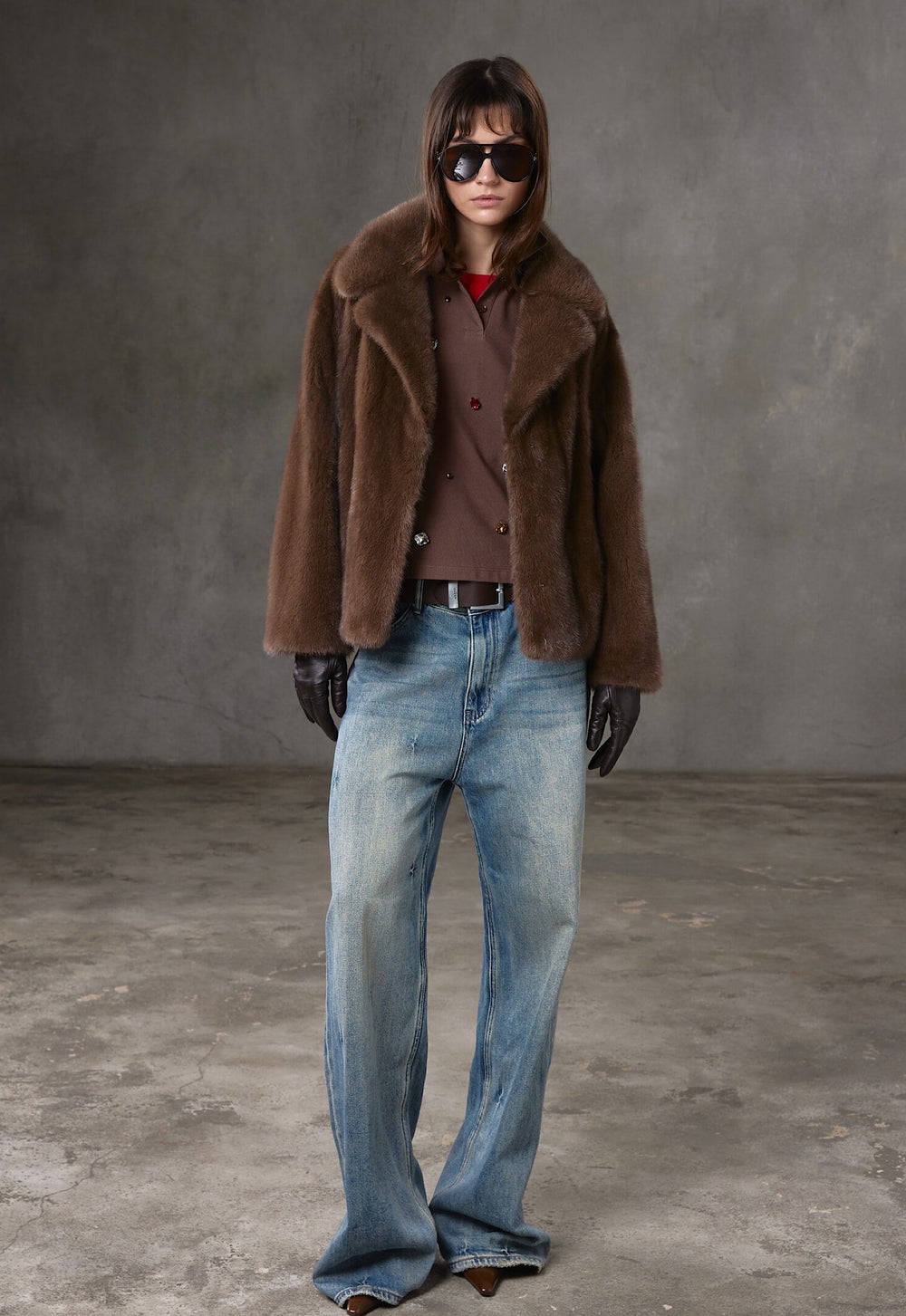 A woman wearing a short brown mink fur coat with a soft, luxurious texture, complemented by trendy sunglasses for a chic, contemporary style.