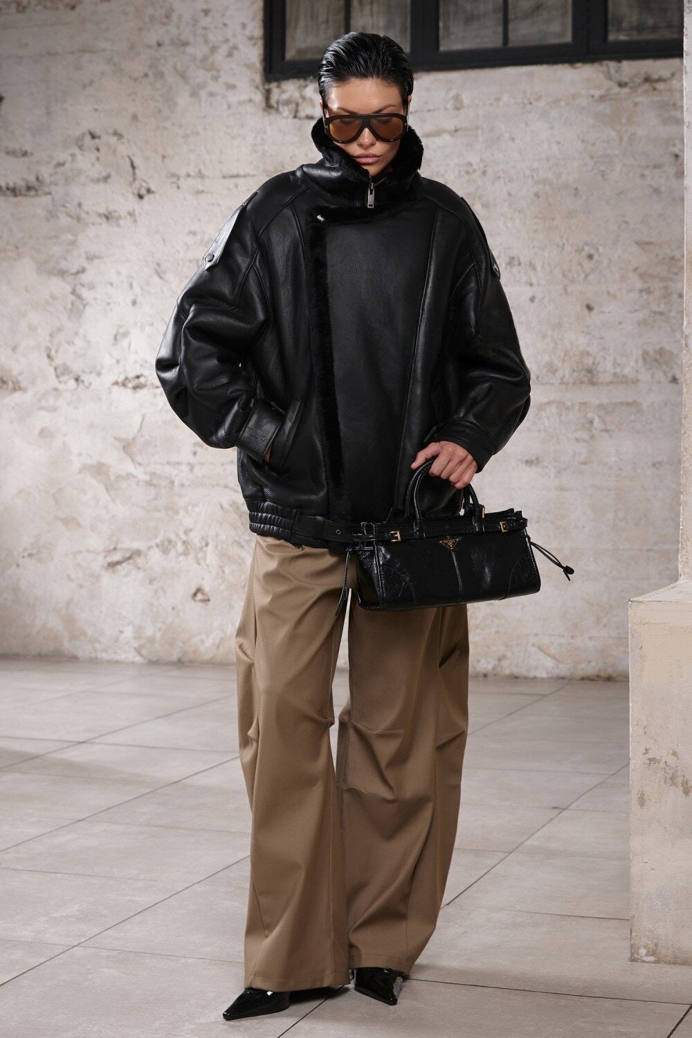 A woman dressed in a high-neck oversized sheepskin jacket with shearling lining, blending comfort with refined style for a sporty, sophisticated appearance.